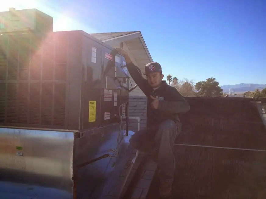 HVAC technician performing AC Tune-Up on a rooftop unit in Tontitown